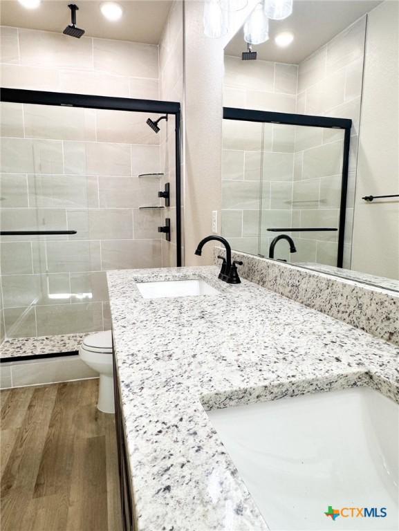 full bathroom with vanity, wood finished floors, a shower stall, and toilet