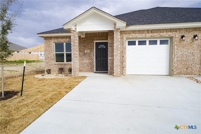 view of front of property featuring brick siding, roof with shingles, concrete driveway, and an attached garage