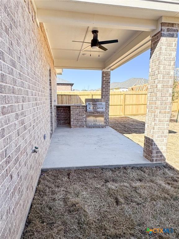 view of patio / terrace featuring area for grilling, an outdoor kitchen, a fenced backyard, and ceiling fan