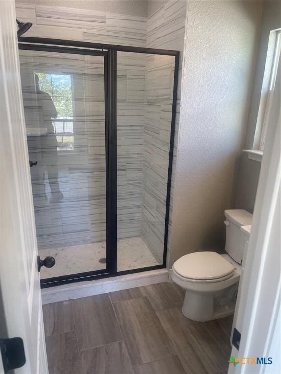 bathroom with a shower with shower door and toilet