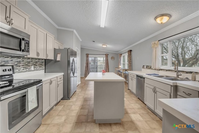 kitchen featuring sink, crown molding, appliances with stainless steel finishes, a kitchen island, and decorative backsplash