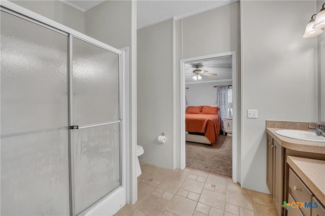 bathroom with a shower with door, ceiling fan, vanity, a textured ceiling, and toilet