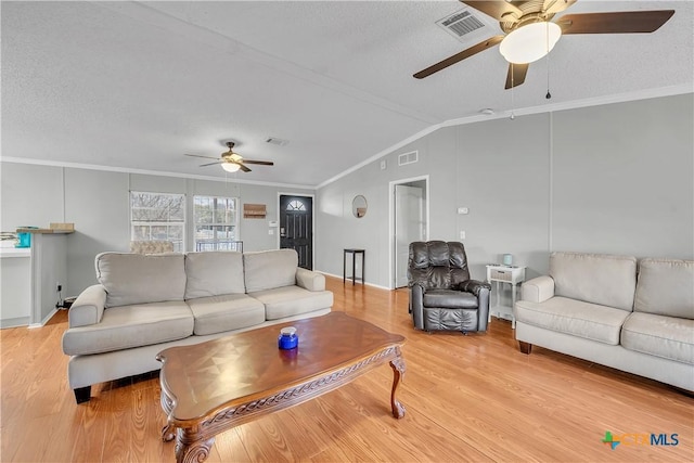 living room featuring vaulted ceiling, a textured ceiling, ornamental molding, ceiling fan, and light hardwood / wood-style floors