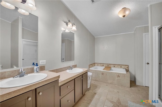 bathroom with tiled tub, vanity, and a textured ceiling