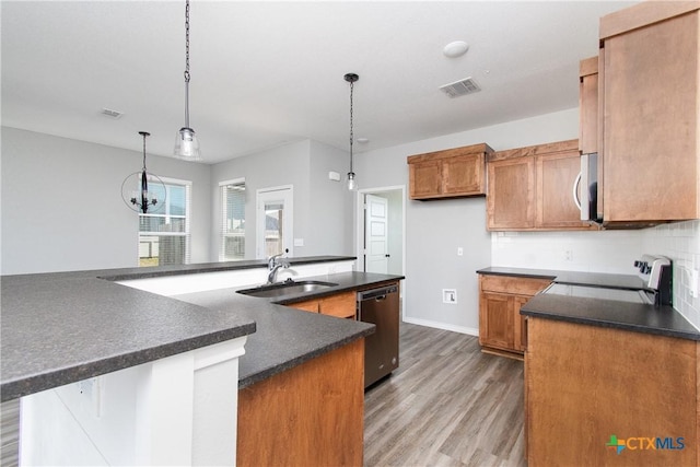 kitchen with hardwood / wood-style floors, sink, decorative backsplash, hanging light fixtures, and stainless steel appliances