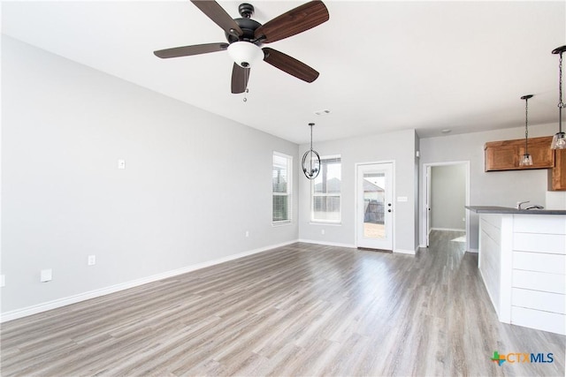 unfurnished living room featuring sink, light hardwood / wood-style flooring, and ceiling fan