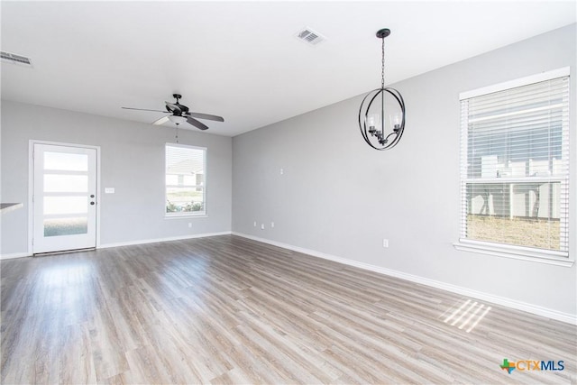 unfurnished living room featuring ceiling fan with notable chandelier and light wood-type flooring