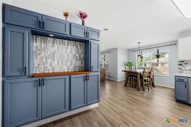 3410 Regency Ct, Killeen, TX 76549 - kitchen featuring baseboards, light wood-type flooring, backsplash, hanging light fixtures, and blue cabinets