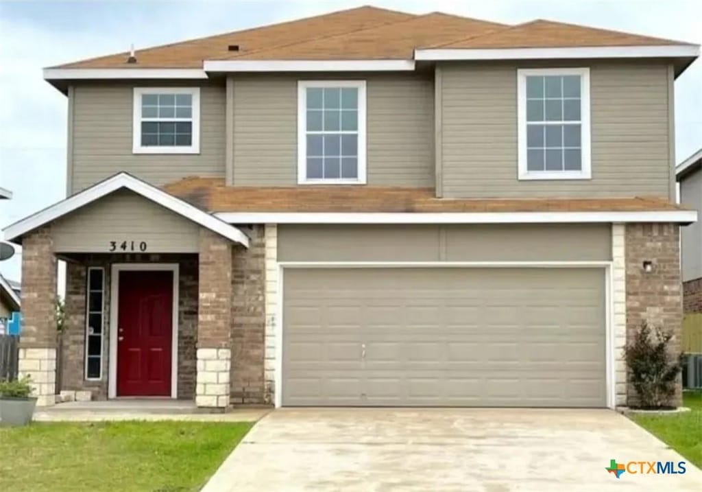 traditional-style house featuring concrete driveway, an attached garage, and stone siding