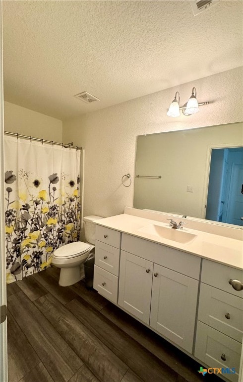 bathroom featuring a textured ceiling, vanity, hardwood / wood-style flooring, toilet, and curtained shower