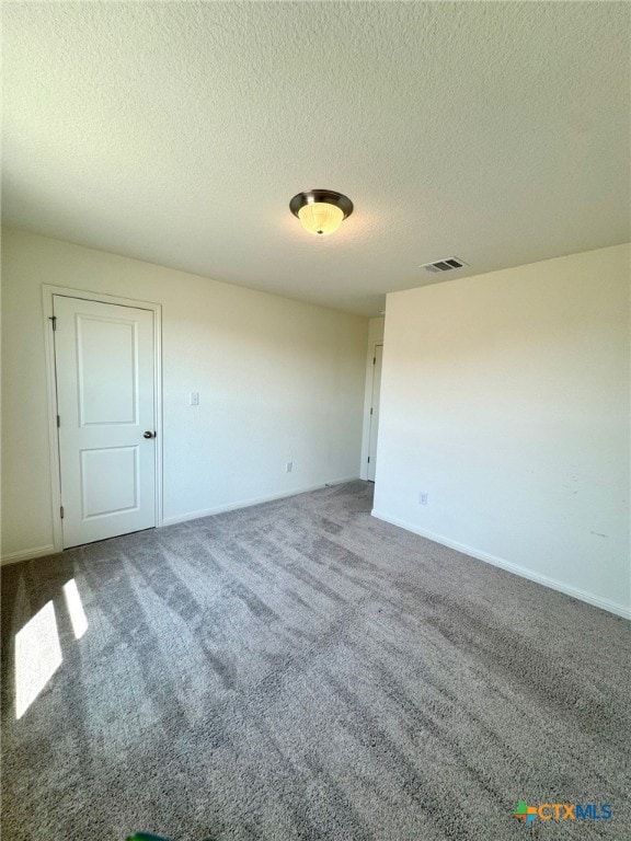 unfurnished room with carpet flooring and a textured ceiling