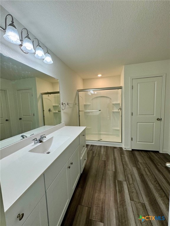 bathroom with hardwood / wood-style floors, vanity, a textured ceiling, and walk in shower