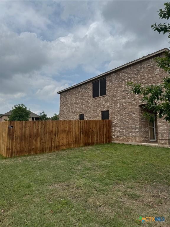 111 Sheep Trail Dr, Kyle, TX 78640 - view of side of home with fence, a lawn, and brick siding
