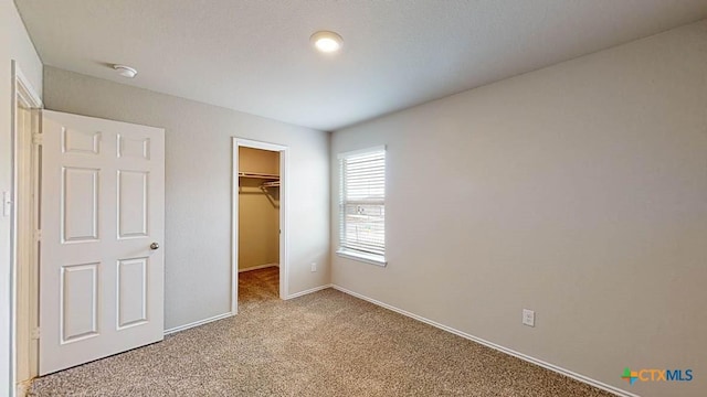 unfurnished bedroom featuring light colored carpet, a closet, and a walk in closet