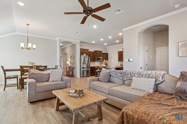 living room featuring visible vents, light wood-style flooring, ceiling fan with notable chandelier, and arched walkways