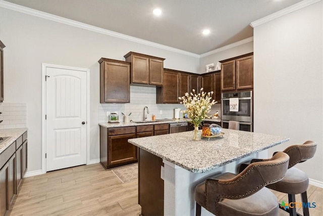 kitchen featuring a kitchen island, a breakfast bar area, light wood-type flooring, stainless steel appliances, and a sink