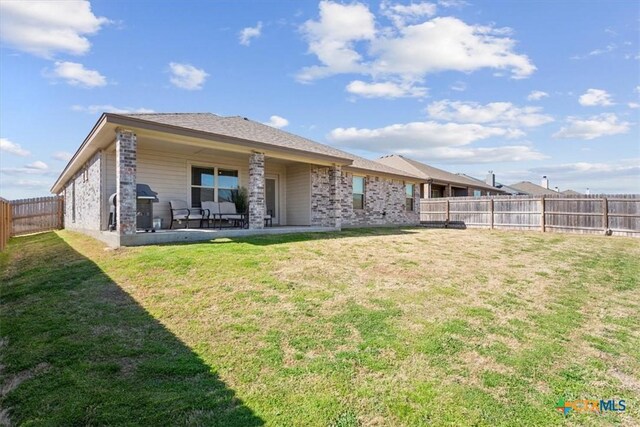 rear view of house featuring a patio, a lawn, and a fenced backyard