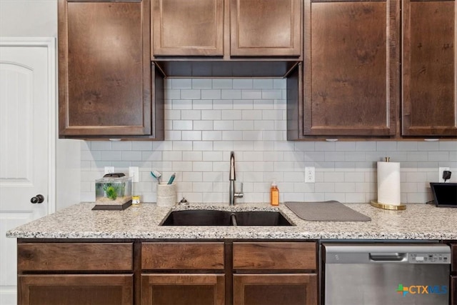 kitchen with a sink, light stone counters, backsplash, stainless steel dishwasher, and dark brown cabinetry