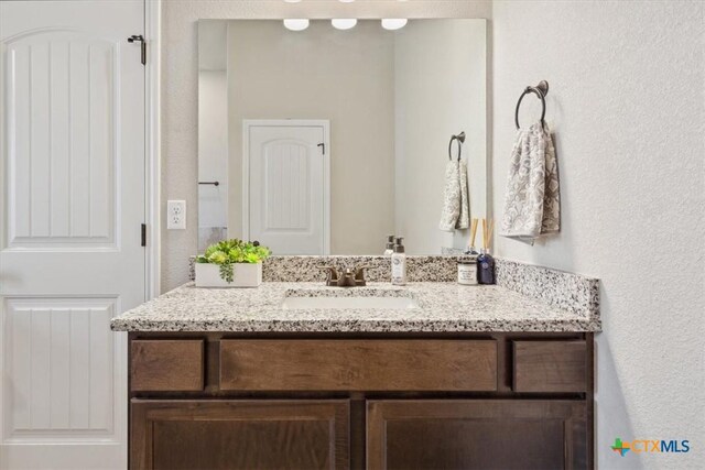 bathroom with vanity and a textured wall