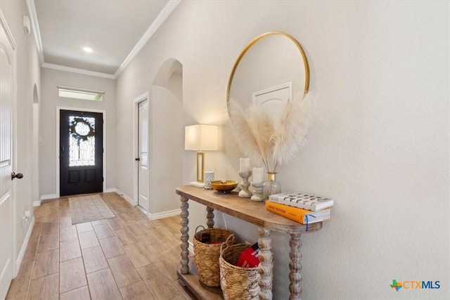 foyer featuring wood finish floors, recessed lighting, arched walkways, crown molding, and baseboards