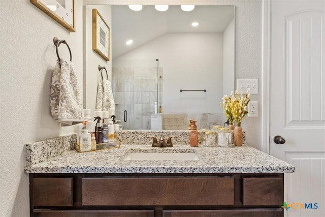 bathroom with a shower stall, vanity, and a textured wall