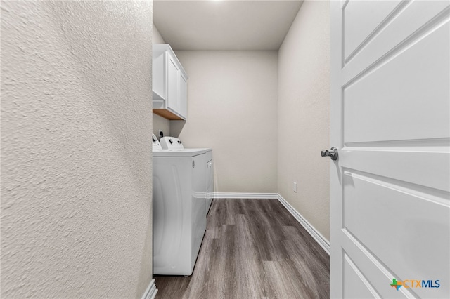 washroom featuring cabinets, dark wood-type flooring, and washing machine and clothes dryer