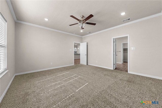 unfurnished bedroom featuring carpet flooring, a walk in closet, ceiling fan, and ornamental molding