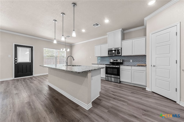 kitchen with a center island with sink, sink, hanging light fixtures, white cabinetry, and stainless steel appliances