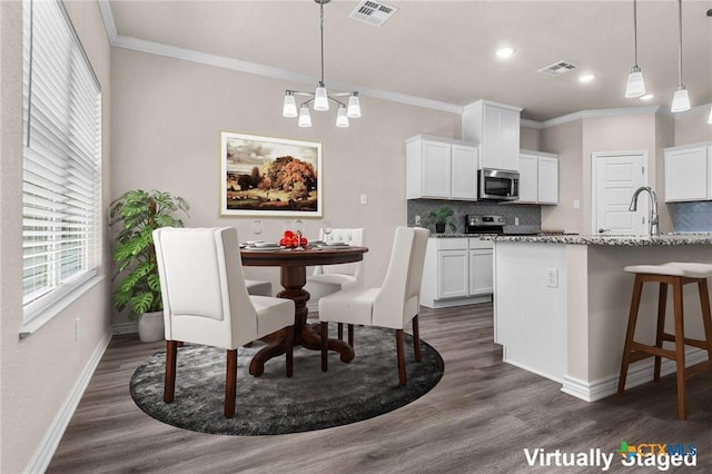 dining room featuring sink, dark hardwood / wood-style floors, and ornamental molding