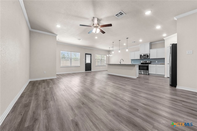 unfurnished living room with ceiling fan, sink, dark hardwood / wood-style flooring, a textured ceiling, and ornamental molding