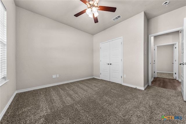 unfurnished bedroom featuring ceiling fan, a closet, and dark carpet