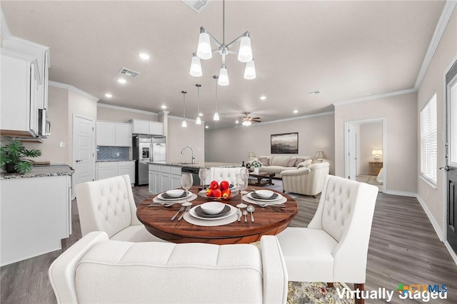 dining room with dark hardwood / wood-style floors, crown molding, sink, and ceiling fan with notable chandelier