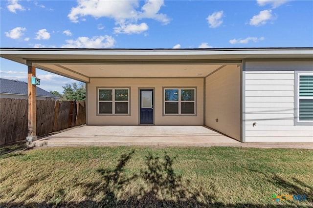 back of property with a lawn and a patio