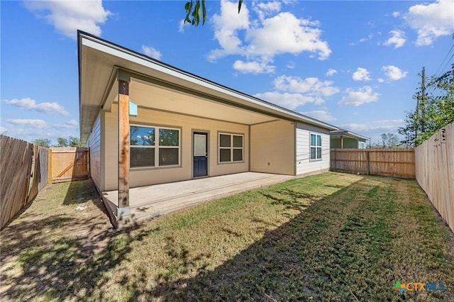 back of house with a yard and a patio