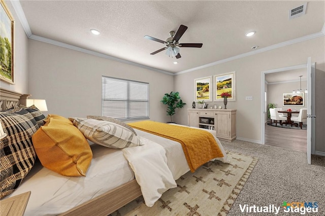 carpeted bedroom featuring ceiling fan, crown molding, and a textured ceiling