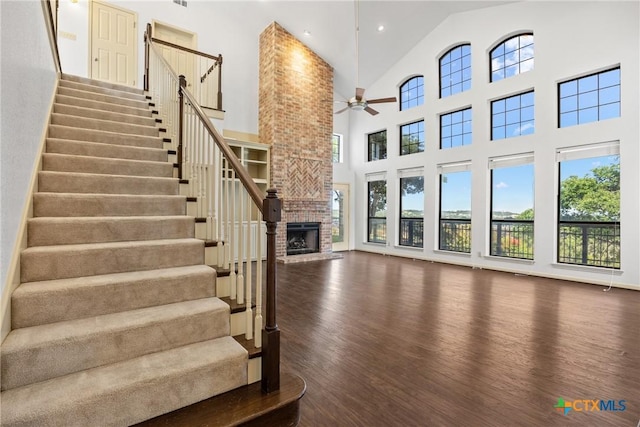 3614 Quail Hollow Rd, Harker Heights, TX 76548 - unfurnished living room featuring wood finished floors, a ceiling fan, a towering ceiling, stairs, and a fireplace
