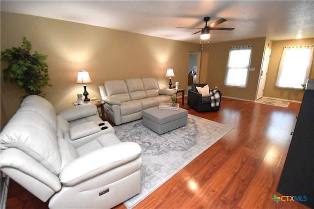living area featuring ceiling fan, baseboards, and wood finished floors