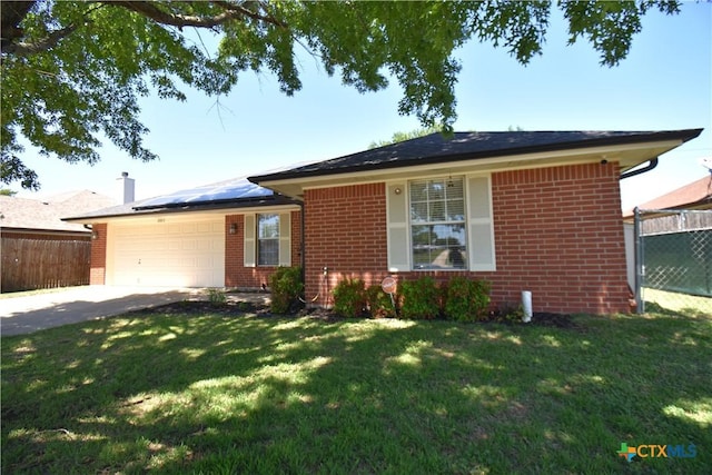 ranch-style house with roof mounted solar panels, fence, concrete driveway, brick siding, and a garage