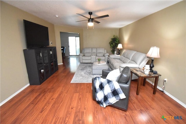 living area featuring ceiling fan, baseboards, and wood finished floors