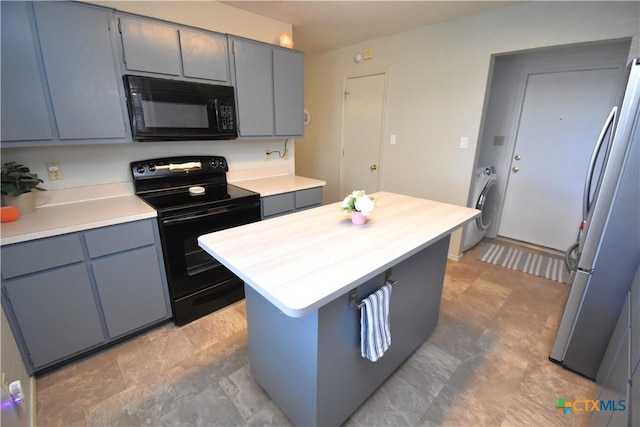 kitchen with washer / dryer, light countertops, gray cabinets, and black appliances