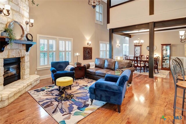 6 Cotswold Ln, Victoria, TX 77904 - living area with a chandelier, wood finished floors, a high ceiling, a stone fireplace, and baseboards