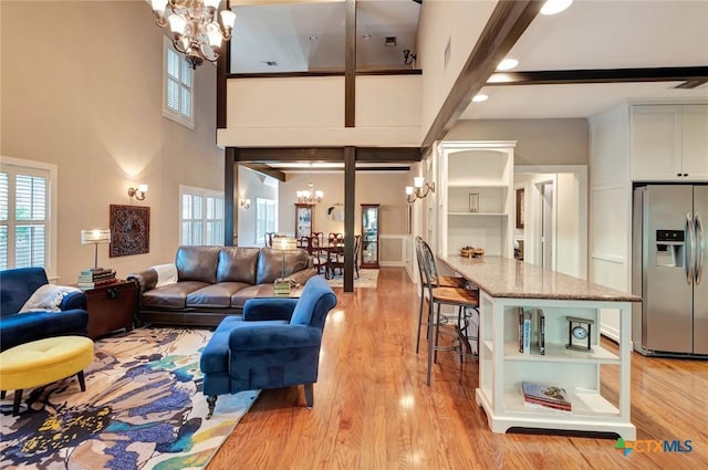 6 Cotswold Ln, Victoria, TX 77904 - living room featuring a chandelier, a towering ceiling, plenty of natural light, light wood-type flooring, and beam ceiling