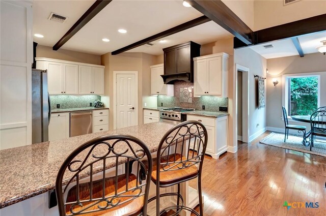 6 Cotswold Ln, Victoria, TX 77904 - kitchen featuring appliances with stainless steel finishes, beamed ceiling, decorative backsplash, baseboards, and light wood-style flooring