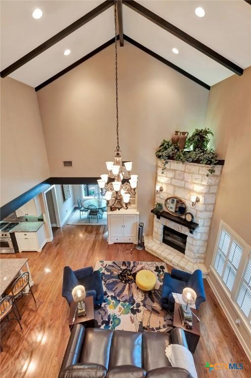 6 Cotswold Ln, Victoria, TX 77904 - living room with wood finished floors, beamed ceiling, high vaulted ceiling, a stone fireplace, and a chandelier