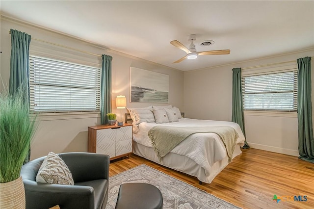 bedroom featuring multiple windows, ceiling fan, and light wood-type flooring