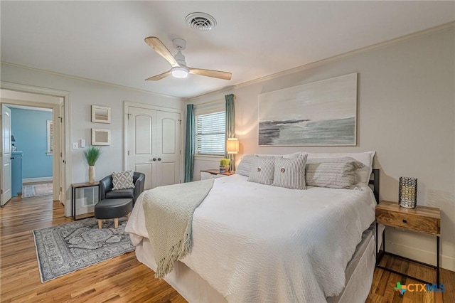 bedroom featuring ornamental molding, ceiling fan, a closet, and hardwood / wood-style floors