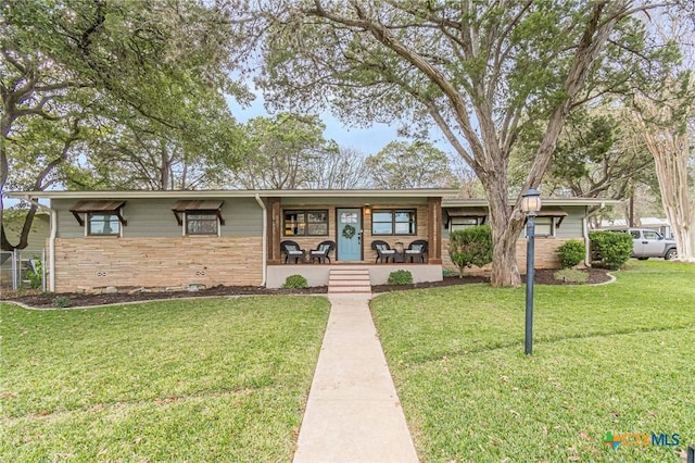 ranch-style house featuring covered porch and a front yard