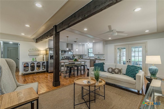 living room with french doors, light wood-type flooring, ceiling fan, and beam ceiling