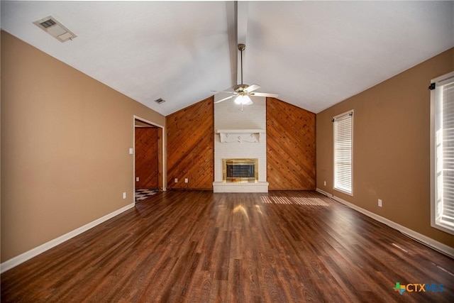 unfurnished living room with wood finished floors, ceiling fan, baseboards, wood walls, and visible vents