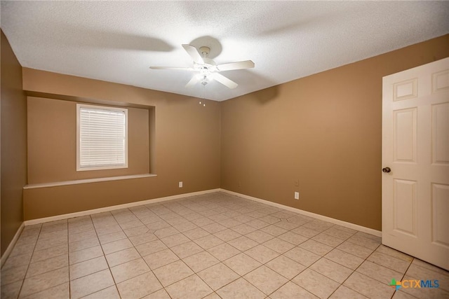 spare room featuring a ceiling fan, baseboards, a textured ceiling, and light tile patterned floors
